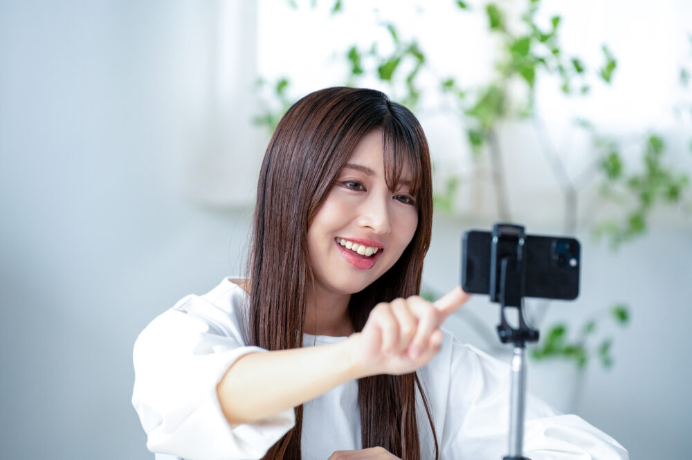 笑顔でスマホを指さす女性