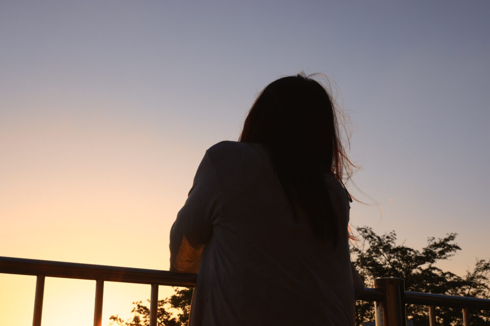 夕暮れに黄昏れる女性